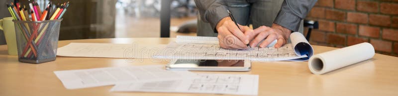 Professional Interior male designer working on blueprints on wood table at workspace. Architect Creative man hands drawing something on paperwork of design building Architecture projects in the office studio