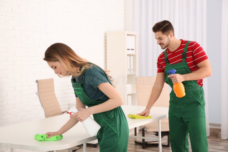 Professional janitors cleaning table in office stock image