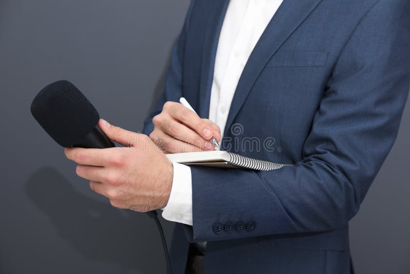 Male Journalist At News Conference, Holding Microphone And Taking Notes
