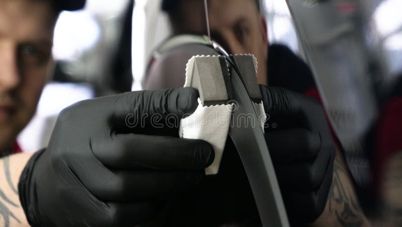 A professional male boy master of ceramics of a car puts ceramics on a car using a fiber sponge rag in a puller, safety goggle