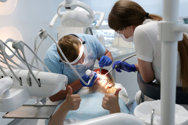 Professional male dentist examining and performing treatment to teenage girl stock images