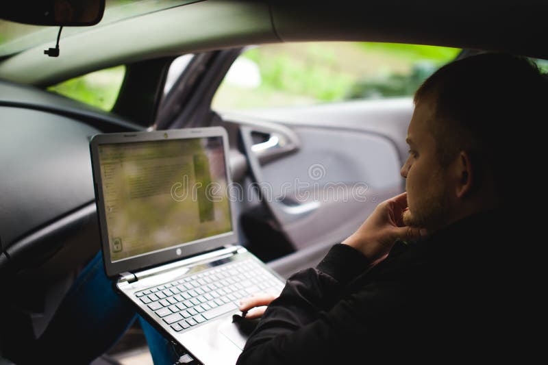 Professional Man with a Laptop in Car Tunes Tuning Control System, Updating Software, Gaining