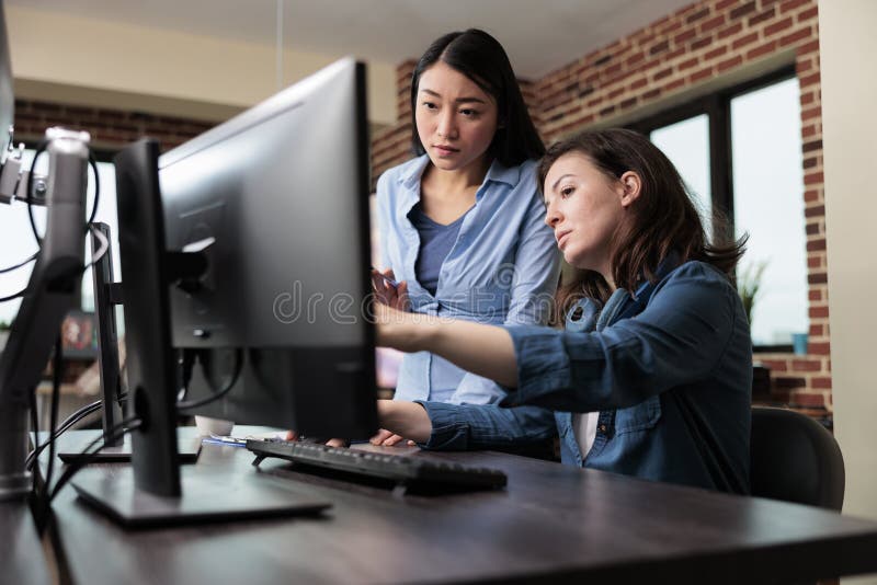 Professional office workers pointing out wrong blueprint of project while using work computer. royalty free stock photography