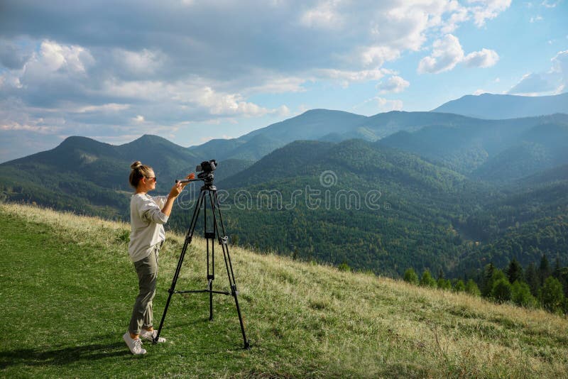 Professional Photographer with Modern Camera on Tripod in Mountains