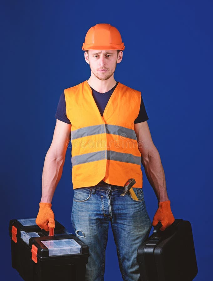 Professional repairman concept. Worker, handyman, repairman, builder on strict face carries bags with professional tools royalty free stock photo Professional repairman concept. Worker, handyman, repairman, builder on strict face carries bags with professional tools royalty free stock photo