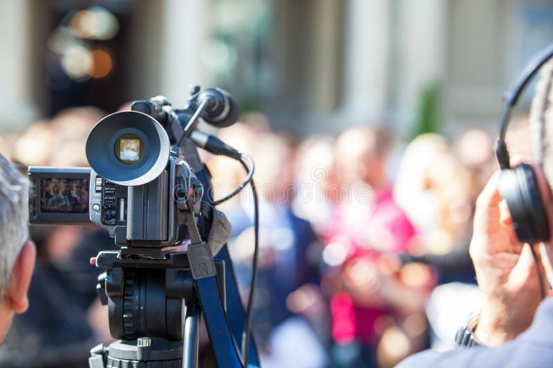Professional video camera recording a media event with a crowd in the background royalty free stock photo