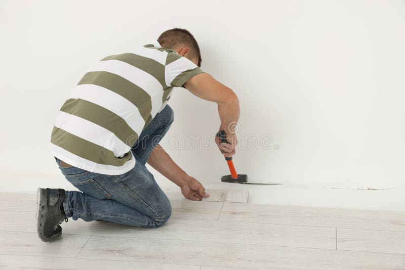 Professional Worker Using Hammer during Installation of New Laminate