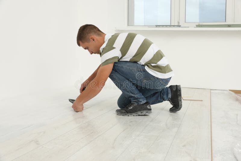 Professional Worker Using Hammer during Installation of New Laminate