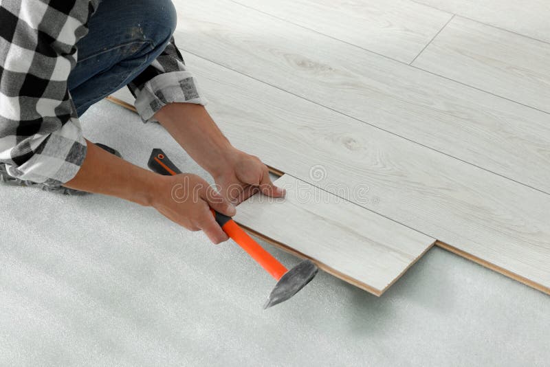 Professional Worker Using Hammer during Installation of New Laminate