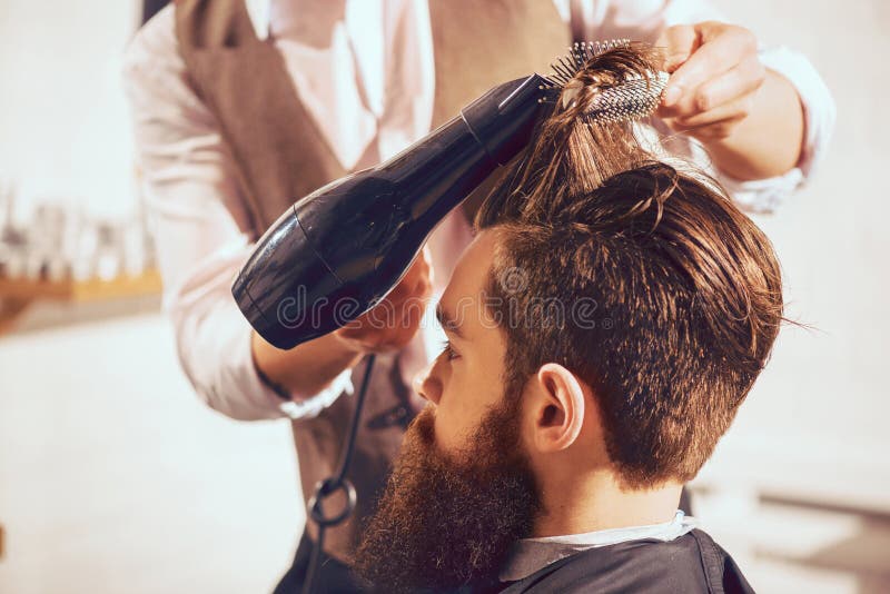 Professioneel kappers drogend haar van zijn cliënt stock fotografie Professioneel kappers drogend haar van zijn cliënt stock fotografie