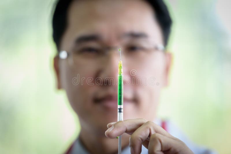 Professionele Aziatische arts met groene spuit en het bespatten royalty-vrije stock foto Professionele Aziatische arts met groene spuit en het bespatten royalty-vrije stock foto