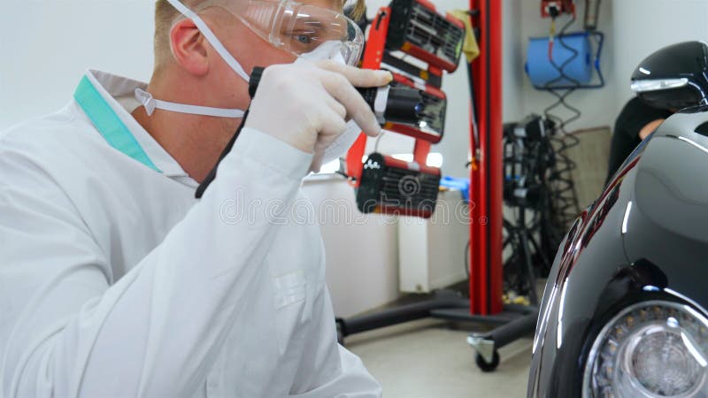 Professionele meester na het polijsten en het schilderen van auto's, controleert de flitslichtkrassen, een ademhaler, witte rubbe stock foto's Professionele meester na het polijsten en het schilderen van auto's, controleert de flitslichtkrassen, een ademhaler, witte rubbe stock foto's