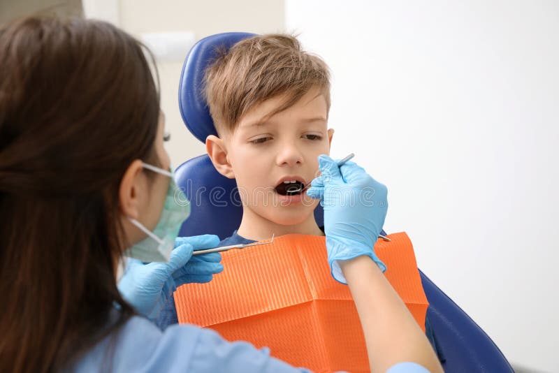 Professionele tandarts die met weinig jongen werken royalty-vrije stock afbeelding Professionele tandarts die met weinig jongen werken royalty-vrije stock afbeelding