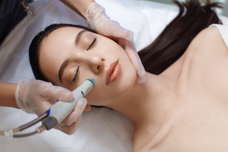 Professionele vrouwelijke cosmetoloog die hydrafaciale procedure toepast in cosmetologische kliniek.