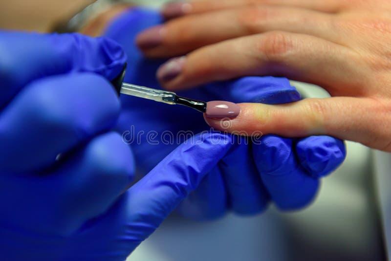 Professionell manikyr, nagellack i skönhetssalon Processen att använda fästlagret på spiken med en pensel fotografering för bildbyråer Professionell manikyr, nagellack i skönhetssalon Processen att använda fästlagret på spiken med en pensel fotografering för bildbyråer