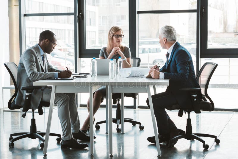 Professionelle multiethnische Geschäftsleute, die bei Tisch zusammenarbeiten stockbild