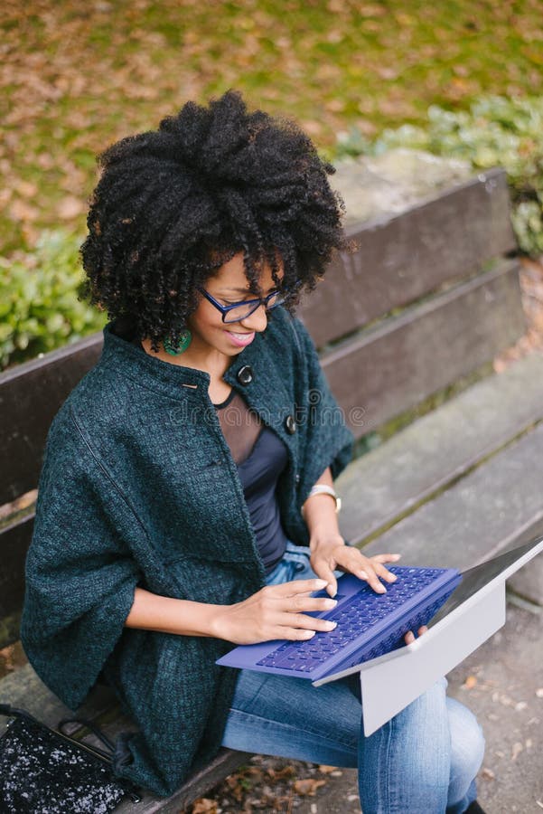 Professionelle schwarze Frau, die mit Laptop draußen im Herbst arbeitet stockbild Professionelle schwarze Frau, die mit Laptop draußen im Herbst arbeitet stockbild