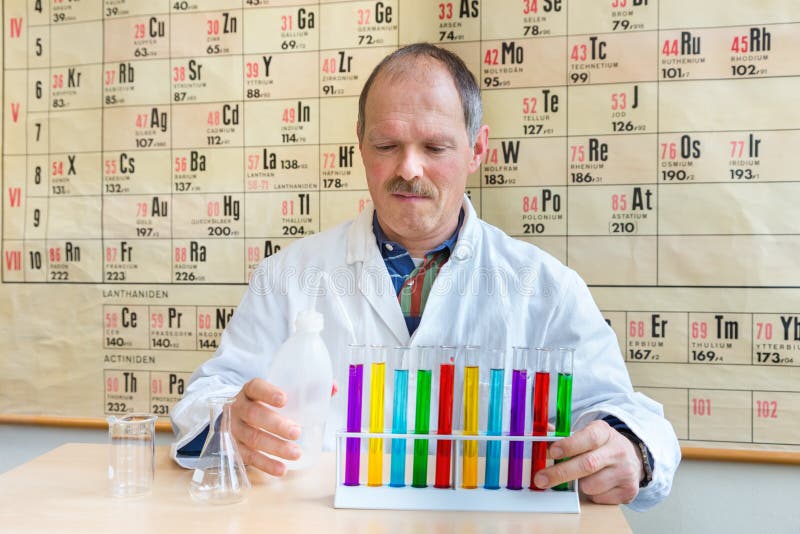 Professor da química que enche os tubos de ensaio coloridos foto de stock Professor da química que enche os tubos de ensaio coloridos foto de stock