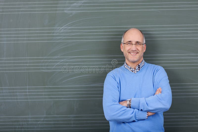 Professor With Hands Folded Standing Against Chalkboard stock images