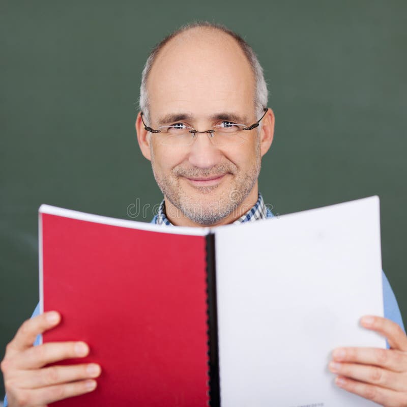Professor Holding Book Against Chalkboard royalty free stock photos