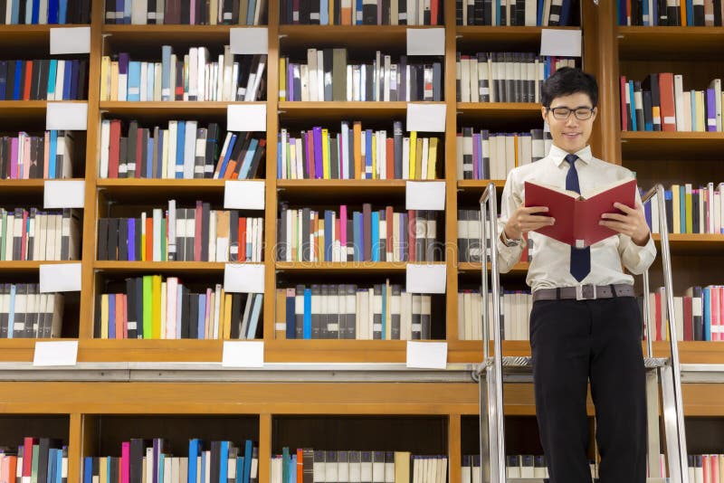 The professor librarian standing on stairs for searching knowledge, reading book in the library