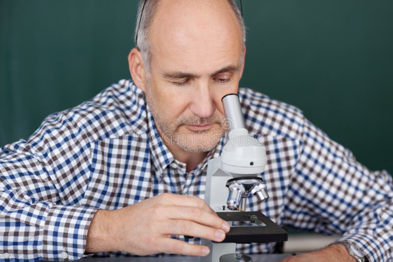 Professor Looking Through Microscope in Wetenschapsklasse stock afbeeldingen Professor Looking Through Microscope in Wetenschapsklasse stock afbeeldingen