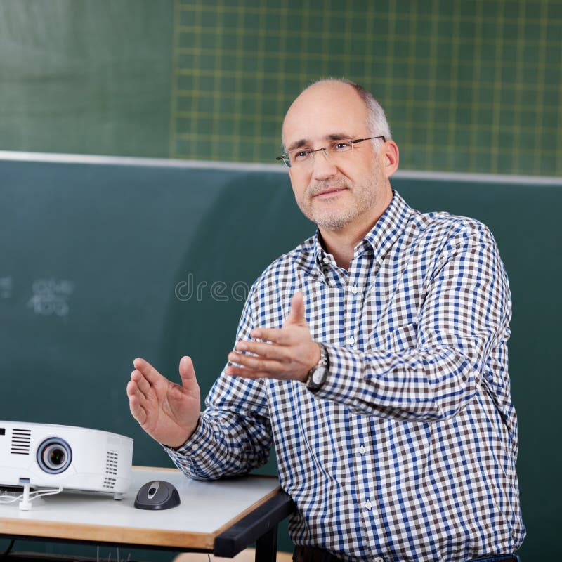 Professor With Projector And Mouse Gesturing In Classroom royalty free stock photo