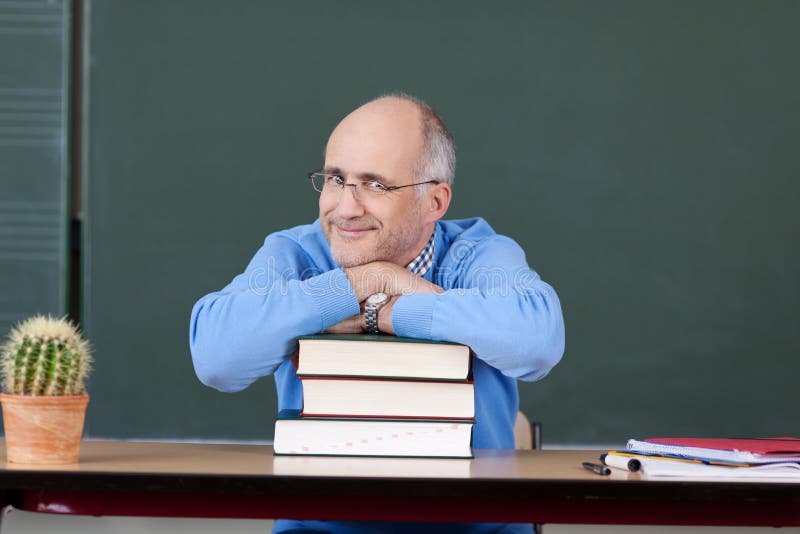 Professor Relaxing On Stacked Books At Desk stock photography
