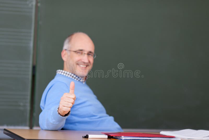 Professor Showing Thumbs Up Gesture At Desk stock photo