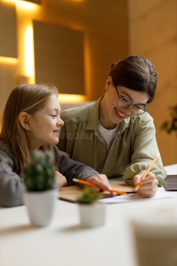 Smiling teacher gives private lessons to a girl child. Smiling teacher gives private lessons to a girl child.