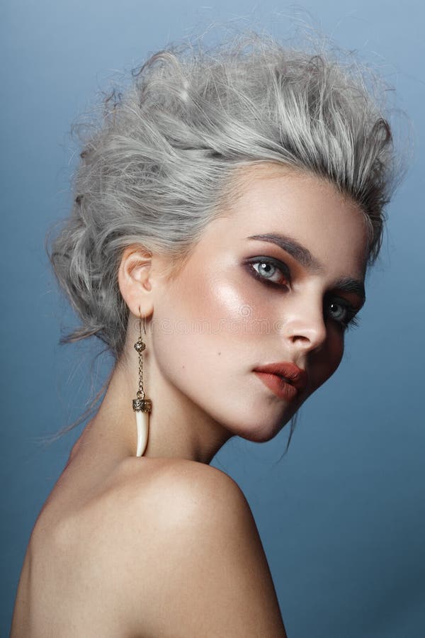 Profiel van mooi jong model met grijs kapsel, naakte die schouders, make-up, smokeyogen, op blauwe achtergrond worden ge?soleerd royalty-vrije stock foto Profiel van mooi jong model met grijs kapsel, naakte die schouders, make-up, smokeyogen, op blauwe achtergrond worden ge?soleerd royalty-vrije stock foto