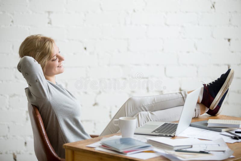 Profielportret van studentenmeisje, benen op bureau, wapens erachter royalty-vrije stock foto Profielportret van studentenmeisje, benen op bureau, wapens erachter royalty-vrije stock foto