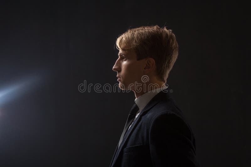 Profil av en ung man i en affärsdräkt på en svart bakgrund arkivbilder Profil av en ung man i en affärsdräkt på en svart bakgrund arkivbilder
