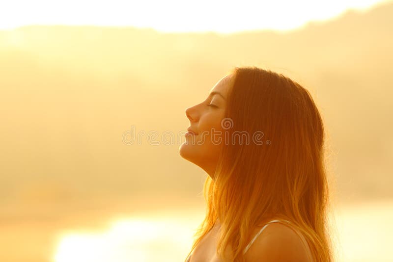 Profile of a relaxed woman at sunset breathing deep fresh air on the beach. Profile of a relaxed woman at sunset breathing deep fresh air on the beach