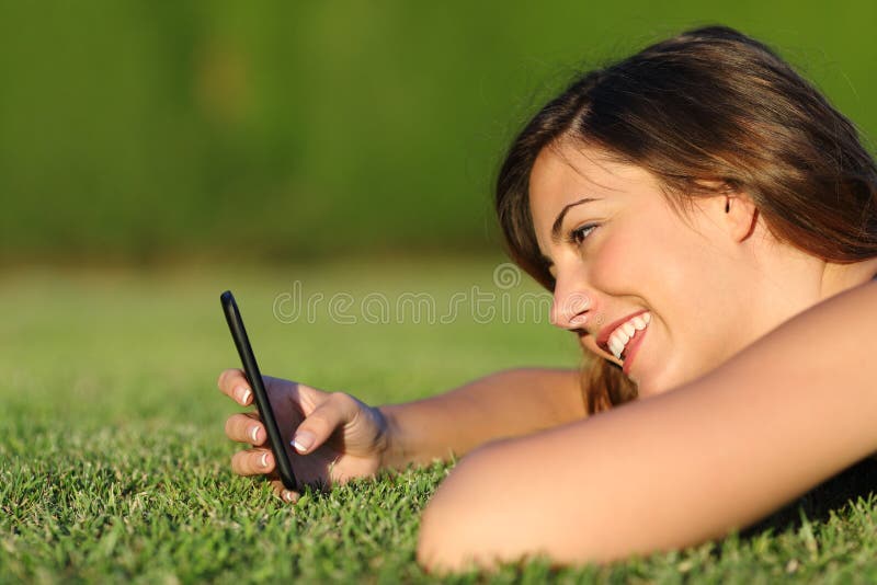 Profile of a funny girl using a smart phone on the grass