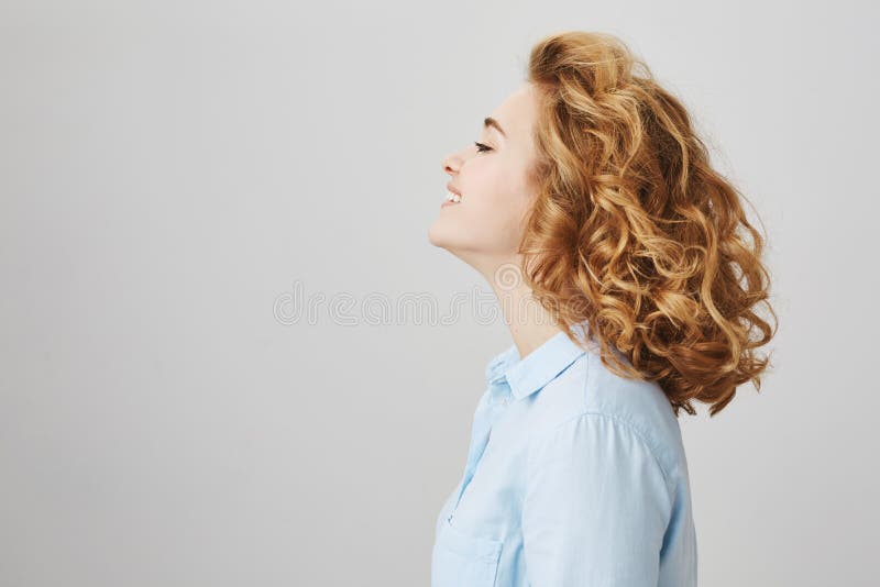 Profile portrait of enjoying happy woman with short curly hair, smiling broadly, wearing casual blue blouse and standing stock image Profile portrait of enjoying happy woman with short curly hair, smiling broadly, wearing casual blue blouse and standing stock image