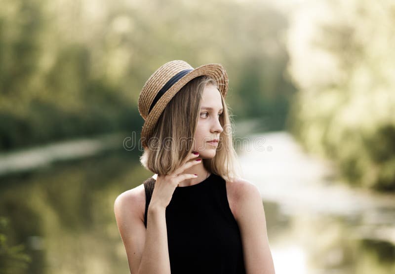 Profile of a pretty girl with short hair in a straw hat over nat
