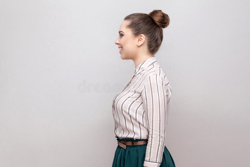 Profile side view portrait of happy beautiful young woman in striped shirt and green skirt with makeup and collected ban hairstyle