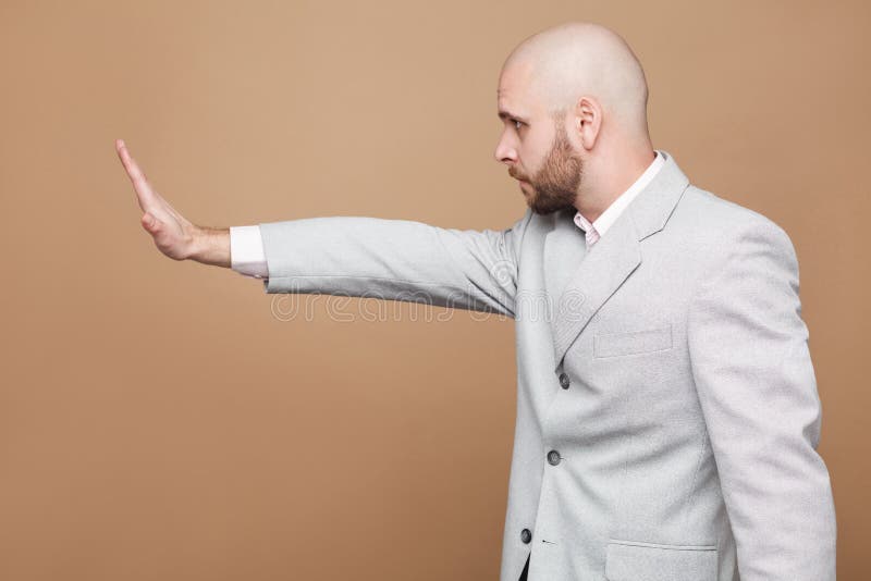 Profile side view portrait of middle aged bald bearded businessman in light gray suit standing with raised arms in stop gesture. stock images Profile side view portrait of middle aged bald bearded businessman in light gray suit standing with raised arms in stop gesture. stock images