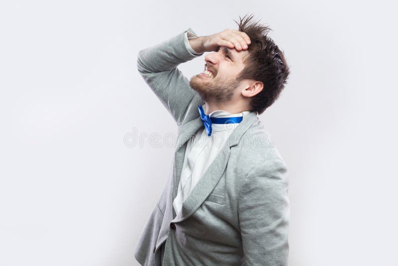 Profile side view portrait of sad handsome bearded man in casual grey suit and blue bow tie standing hopeless because he lose royalty free stock photography Profile side view portrait of sad handsome bearded man in casual grey suit and blue bow tie standing hopeless because he lose royalty free stock photography