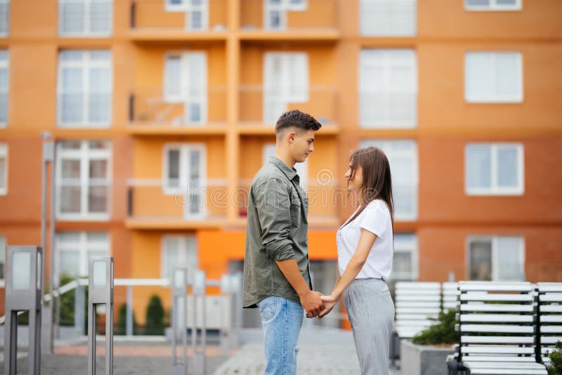 Profilez la vue d'un jeune couple attrayant tenant des mains et regardant l'un l'autre image stock Profilez la vue d'un jeune couple attrayant tenant des mains et regardant l'un l'autre image stock