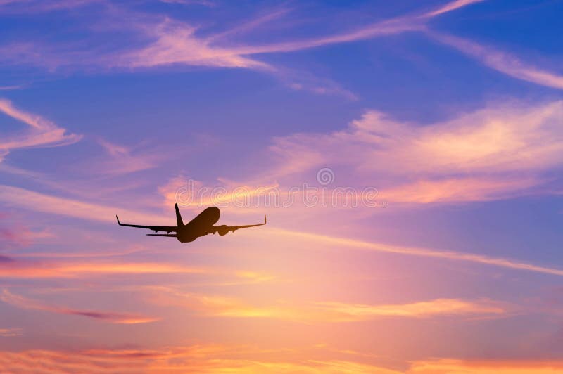 Profili l'aeroplano del passeggero che vola via dentro all'altitudine molto in alto durante il tempo del tramonto