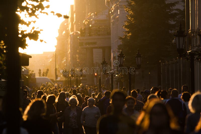 Profili la folla della gente che cammina giù la zona pedonale al tramonto di sera dell'estate immagine stock libera da diritti Profili la folla della gente che cammina giù la zona pedonale al tramonto di sera dell'estate immagine stock libera da diritti