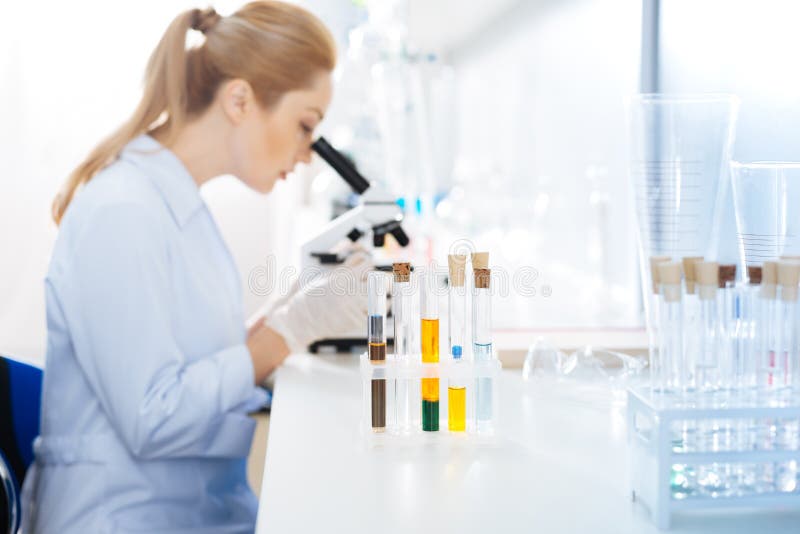 Profili la foto dell'assistente serio quel microscopio esaminante fotografia stock libera da diritti Profili la foto dell'assistente serio quel microscopio esaminante fotografia stock libera da diritti