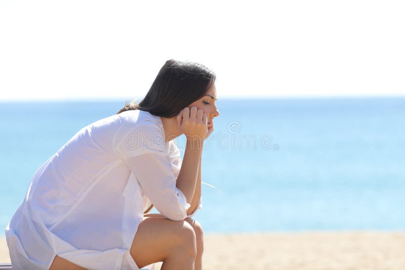Profilo di una donna preoccupata che si siede sulla spiaggia fotografia stock Profilo di una donna preoccupata che si siede sulla spiaggia fotografia stock