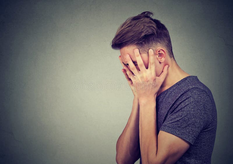 Profilo laterale di un giovane triste con le mani sul fronte che guarda giù Depressione e disturbo di ansia Profilo laterale di un giovane triste con le mani sul fronte che guarda giù Depressione e disturbo di ansia