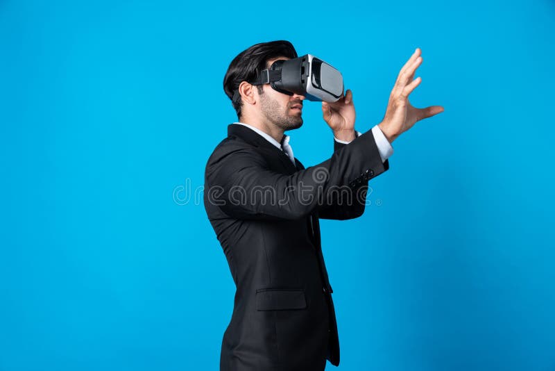 Professional smart business man holding something while wearing VR glasses. Caucasian project manager with virtual reality goggles while present technology innovation with blue background. Deviation. Professional smart business man holding something while wearing VR glasses. Caucasian project manager with virtual reality goggles while present technology innovation with blue background. Deviation.