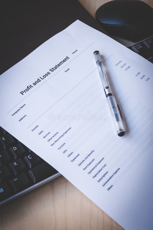 Profit and Loss Statement on Black Keyboard and Brown Leather Notebook on Pine Desk stock photo