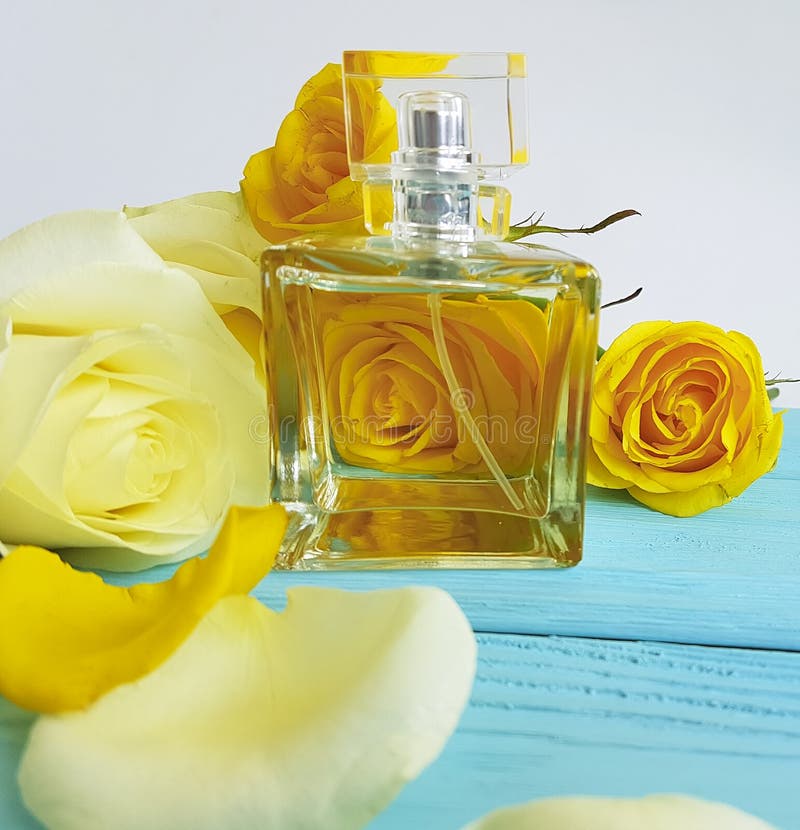 Profumi la bottiglia dell'aroma dell'essenza con le rose gialle su un fondo di legno fotografia stock libera da diritti Profumi la bottiglia dell'aroma dell'essenza con le rose gialle su un fondo di legno fotografia stock libera da diritti