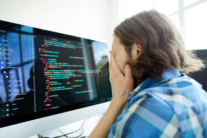 Programador de computador forçado na frente do computador imagem de stock Programador de computador forçado na frente do computador imagem de stock